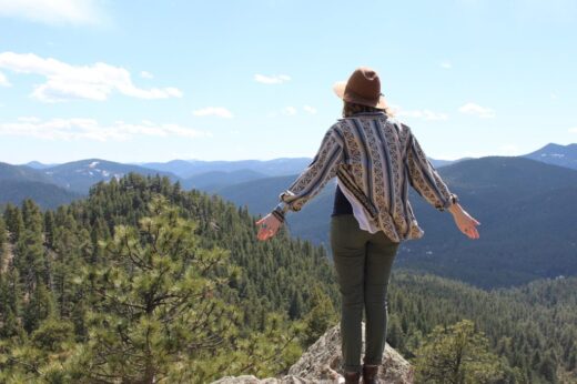 young woman on overlook with arms open