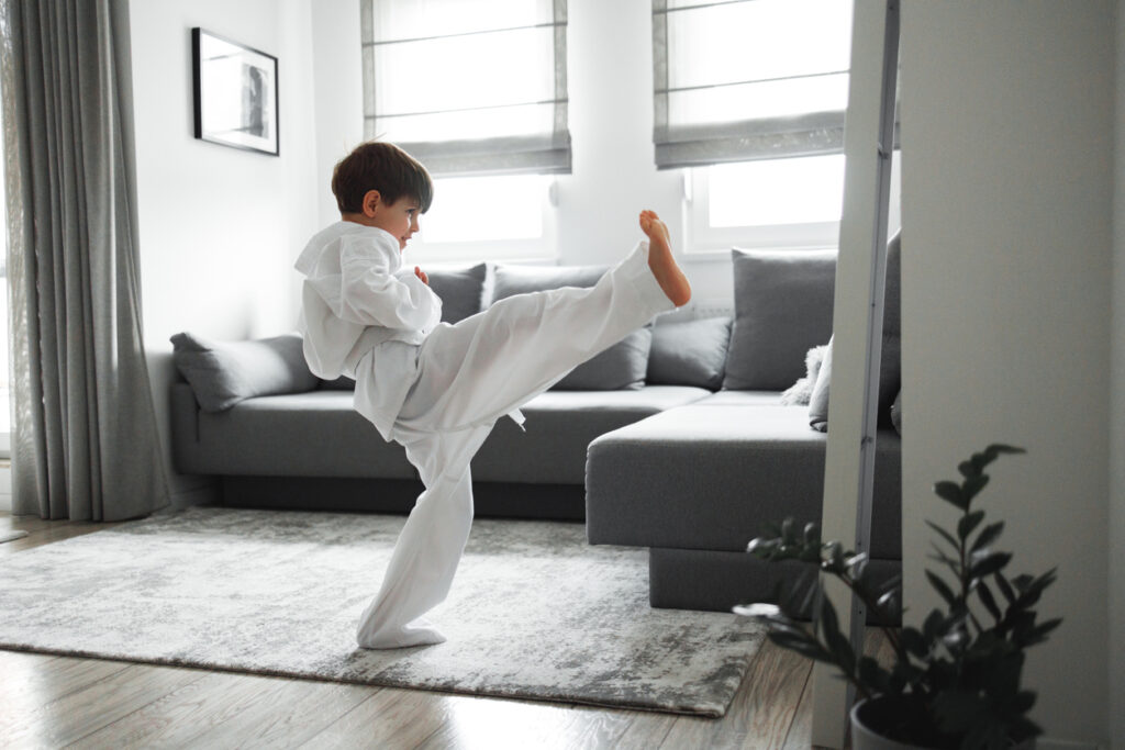 7 years old boy dressed in kimono, training taekwondo at home.